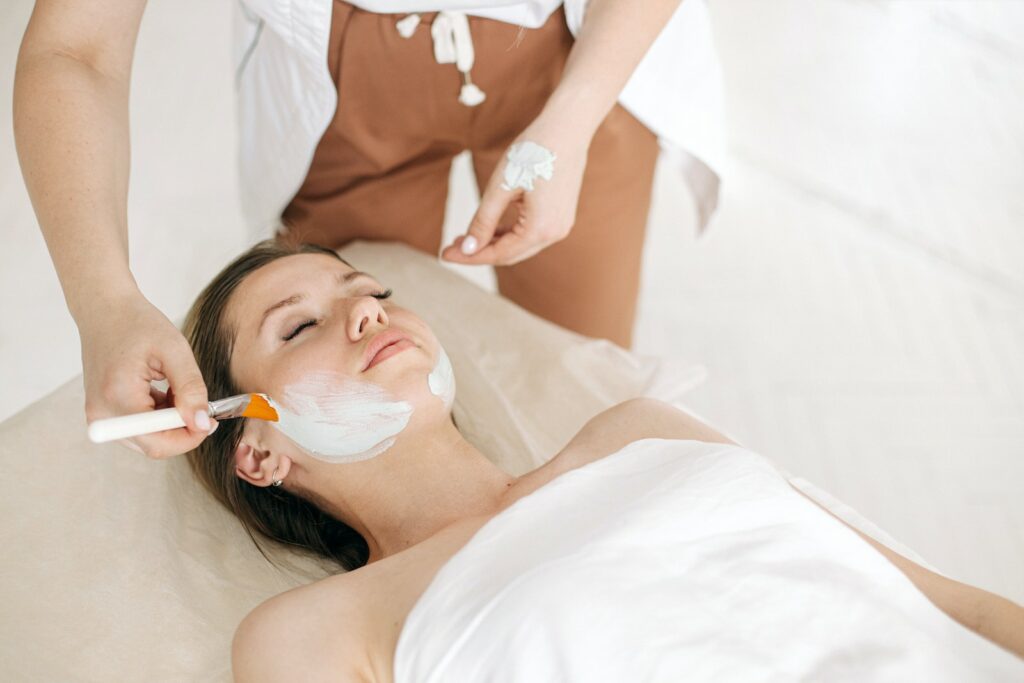 A Person Applying Facial Mask on Woman's Face